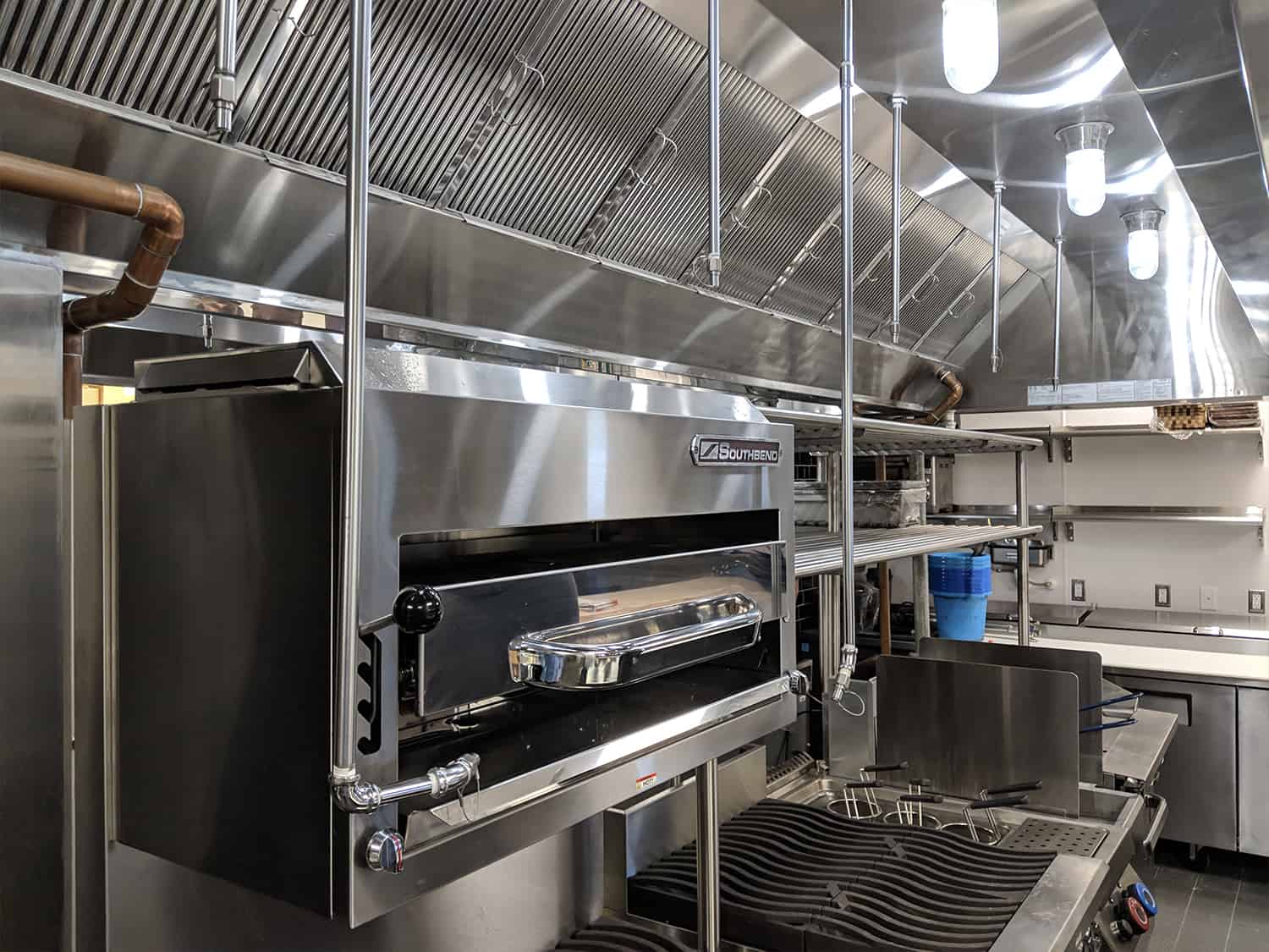 Industrial bakery oven with trays and stainless steel surroundings.