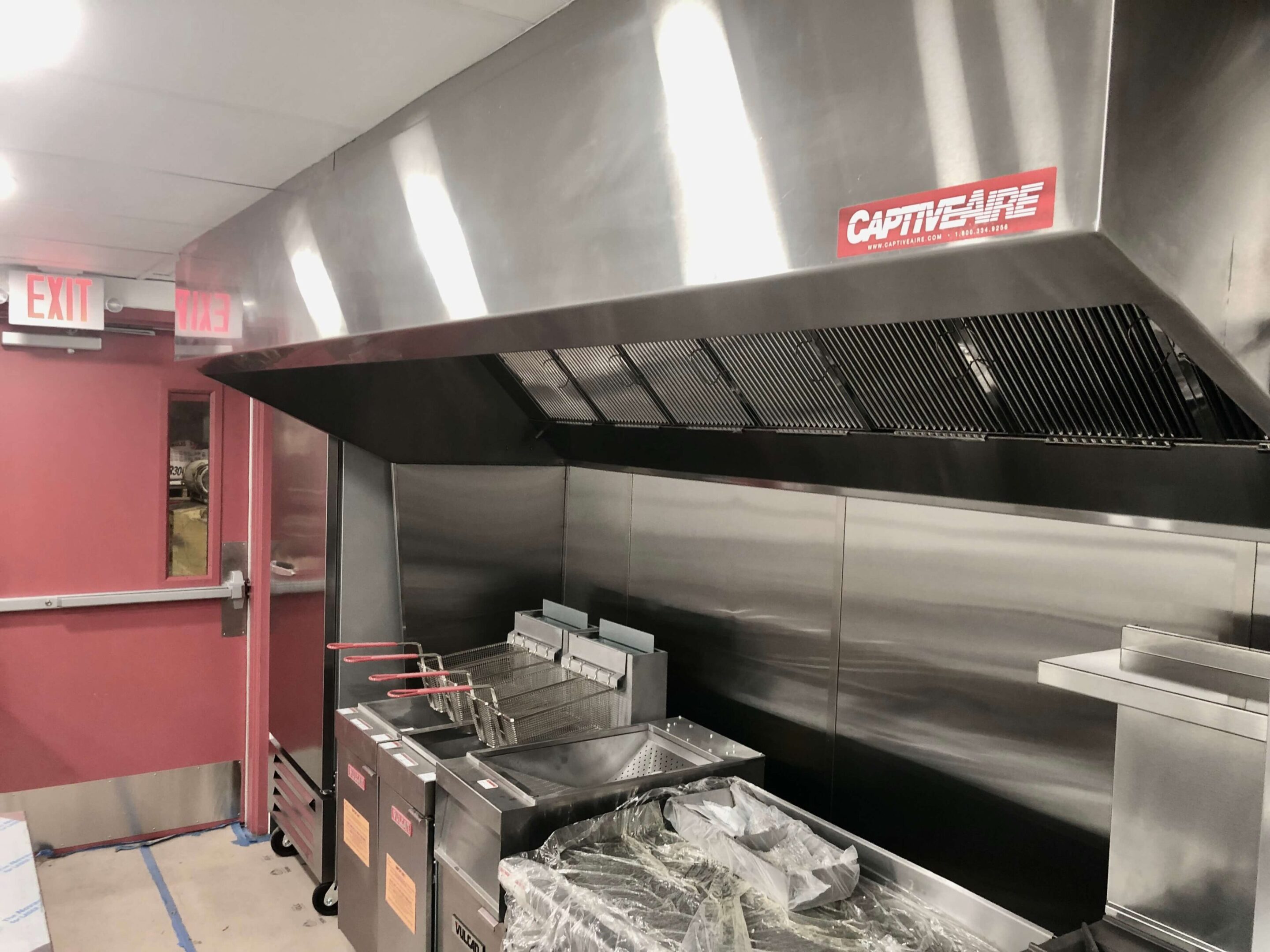 Commercial kitchen with stainless steel appliances and ventilation hood.