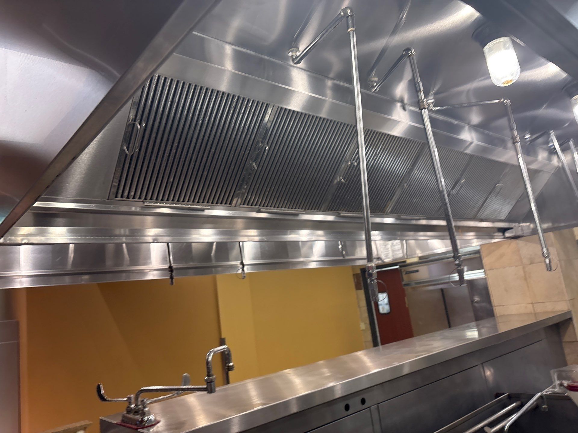 A commercial kitchen exhaust hood with stainless steel surfaces.