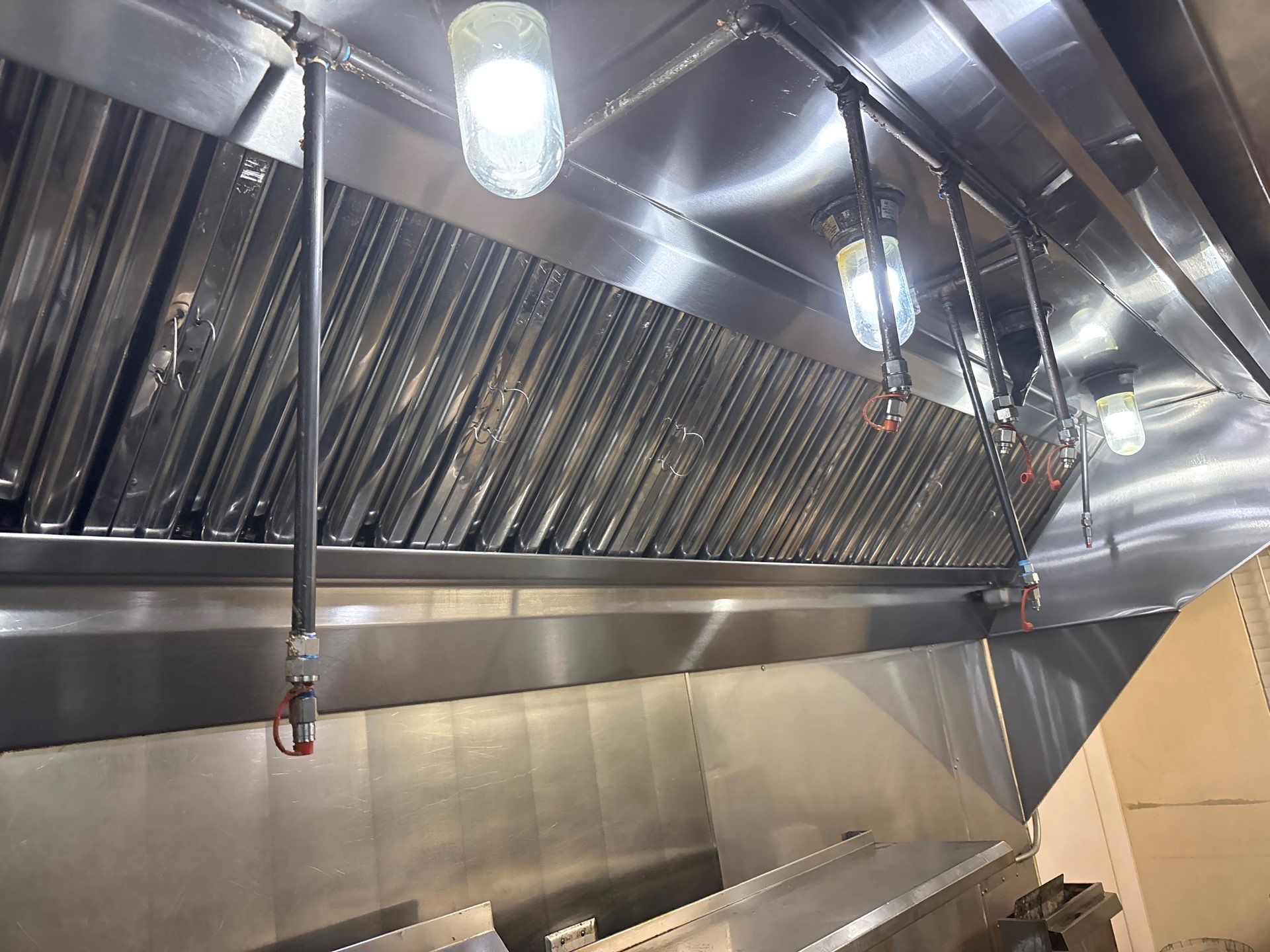 A commercial kitchen hood and exhaust system above a cooking area.